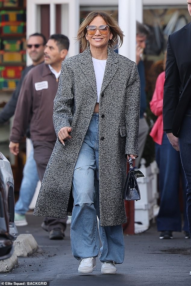 She flashed her toned midriff in a combination of a classic white cropped top and baggy blue jeans