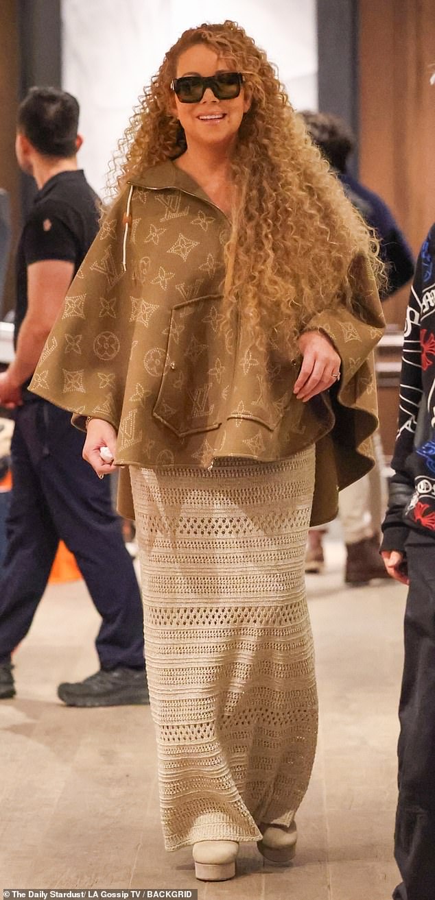 At Louis Vuitton, the Heartbreaker hitmaker tried on a brown poncho with the fashion house's LV logo embossed all over