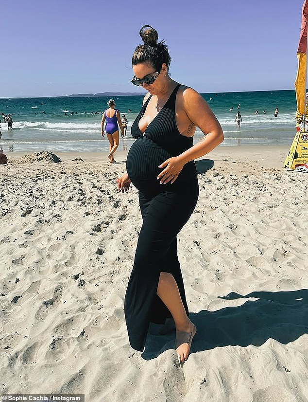 She shared a series of photos of her cradling her blossoming baby bump as she smiled on the beach in Noosa and left some name suggestions in a caption