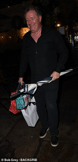 Piers cut a smart figure in a black shirt and jeans as he left the event carrying three bags of gifts and an umbrella