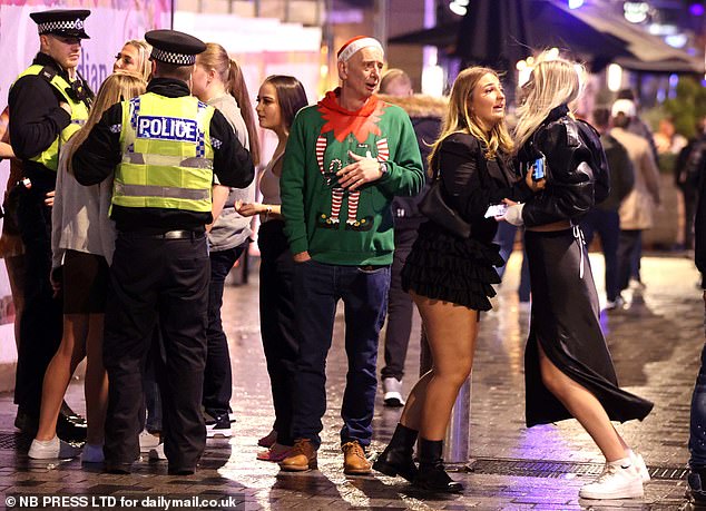 LEEDS: A woman is held back by her friend as police officers and a man in an elf sweater look on