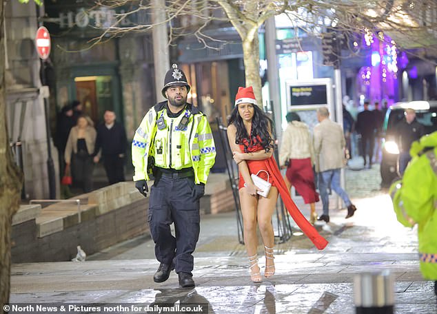 NEWCASTLE: A woman wearing a Santa hat holds her handbag as she walks down the street with a police officer