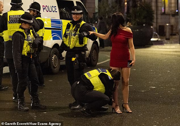 CARDIFF: A police officer adjusts the shoe strap of a partygoer in Cardiff on Friday evening