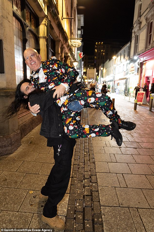 CARDIFF: A reveler hoists his friend, dressed in a cute Christmas suit, high into the air