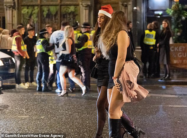 CARDIFF: Two women, one in a Santa hat, stroll down the street, oblivious to the chaos behind them