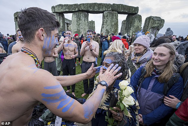 A person's face is daubed with blue paint as he takes part in the winter solstice celebrations at Stonehenge, England, Saturday