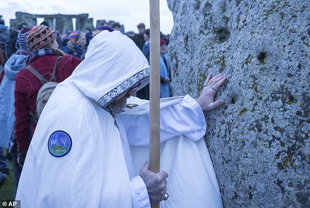 A man lays hands on one of the stones during the winter solstice celebration at Stonehenge today