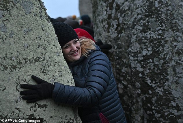 A reveler interacts with a stone as people gather to celebrate the pagan festival 'Winter Solstice' at Stonehenge