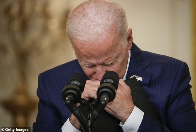 US President Joe Biden pauses and clutches his folder as he listens to a question from a reporter