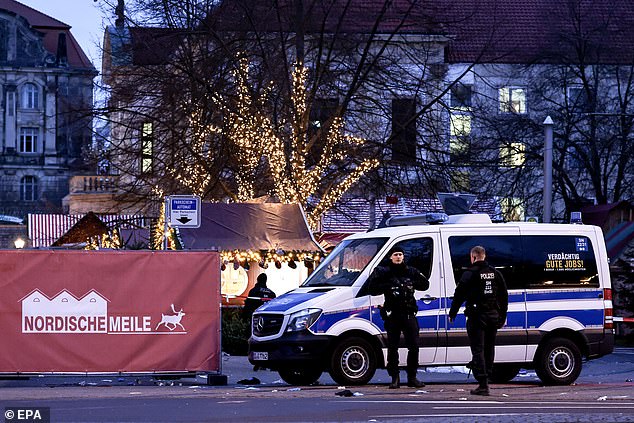 German police officers stand guard next to their vehicle at the scene of a car ram attack at the Christmas market in Magdeburg, Germany, December 21, 2024. According to Magdeburg police, at least two people were confirmed dead, dozens were injured and the suspect, a Saudi national, was taken into custody