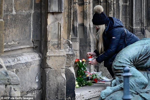 A mourner lights a candle today at the Christmas market, where the night before a car crashed into a crowd, killing at least two people and injuring more than 60 people. At least two people were killed and more than sixty were injured