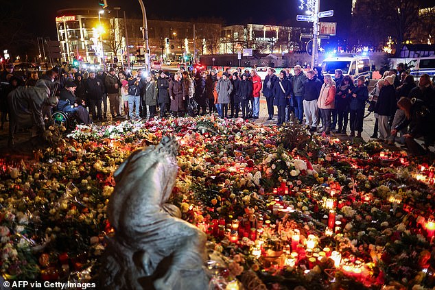 People lay flowers at a makeshift memorial near the site of a car ram attack at a Christmas market in Magdeburg