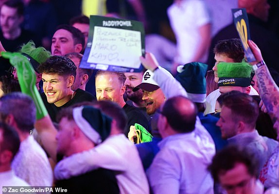 Aston Villa player Matty Cash (centre) on day seven of the Paddy Power World Darts Championship at Alexandra Palace, London. Date of photo: Saturday, December 21, 2024. PA Photo. See PA story DARTS World. Photo credit should read: Zac Goodwin/PA Wire. RESTRICTIONS: Use subject to restrictions. Editorial use only, no commercial use without prior permission from the rights holder.