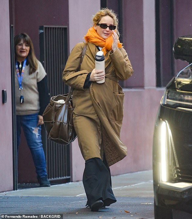 The 34-year-old actress looked cozy, wearing a tan trench coat over sweaters and slacks and wearing a chic orange scarf