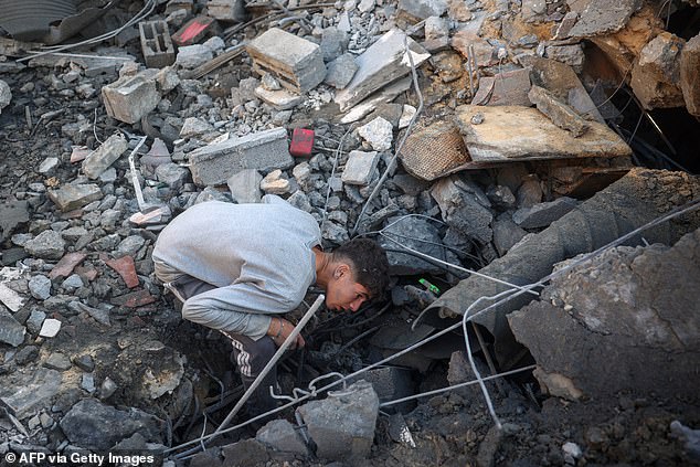 A youth searches for survivors at the site of an Israeli attack on the Abu Samra family home in Deir el-Balah in the central Gaza Strip on December 22, 2024