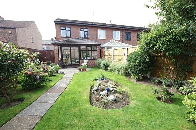 The house from the backyard with stone path and manicured lawn