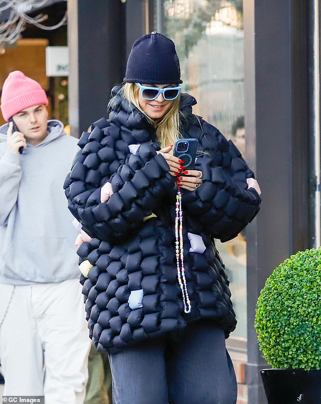 The blonde beauty added a black beanie and blue framed sunglasses to her casual look