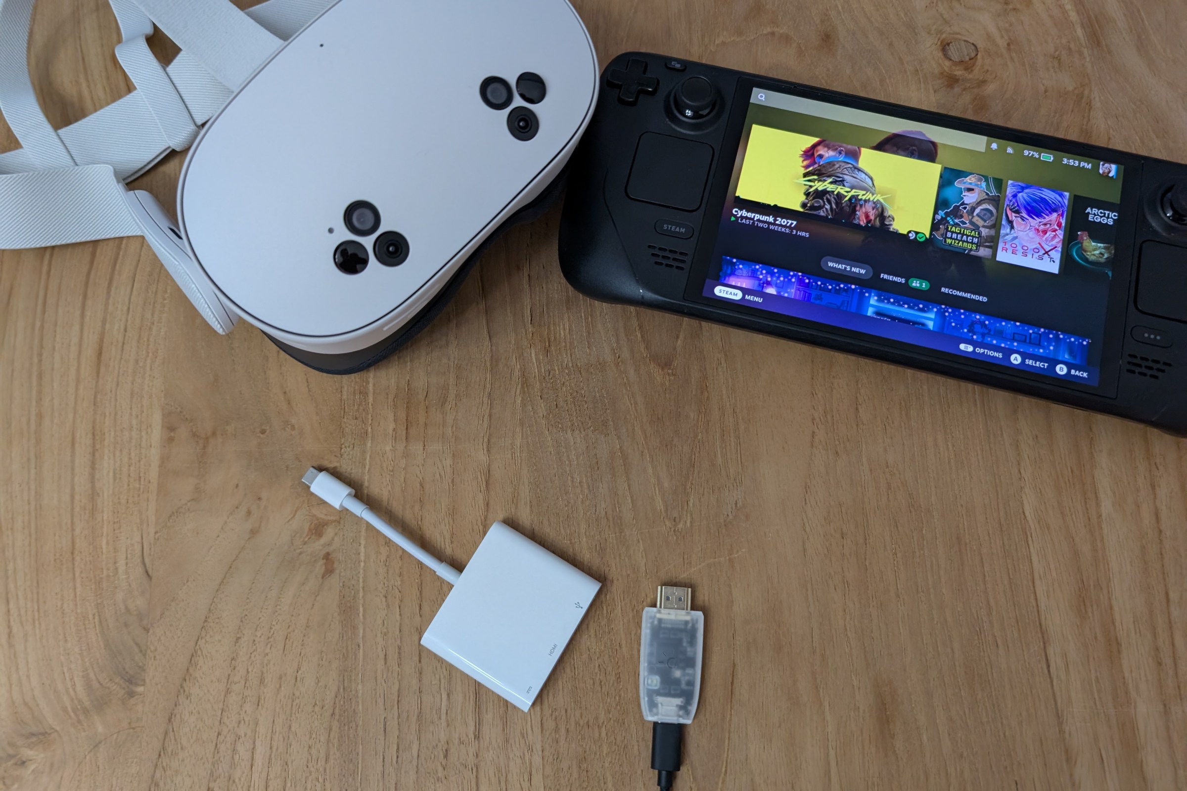 An image of multiple devices laid out on a wooden table, including a Meta Quest 3S VR headset, a USB-C hub, a Genki ShadowCast 2 capture card, and a Steam Deck OLED.