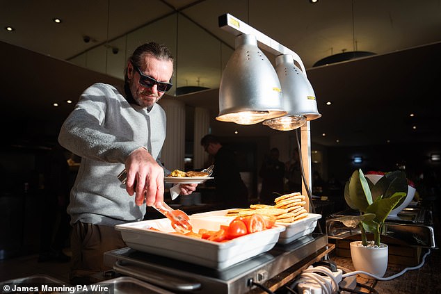 A man helps himself to a breakfast meal at the opening of Crisis's Christmas services in central London, as the charity sees unprecedented demand to help people sleeping rough