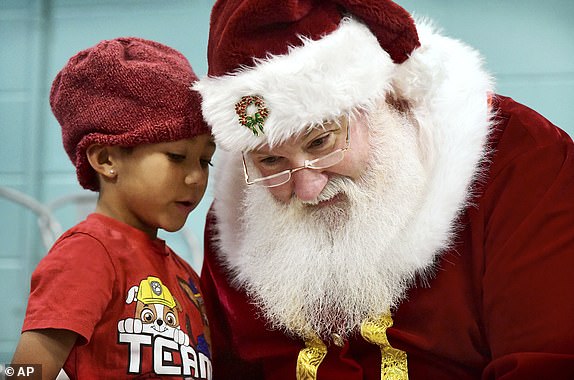 Zane Castello, 6, whispers his Christmas wish to Santa Claus during the Winter Day Camp holiday party at the Greater Johnstown Community YMCA in Johnstown, Pennsylvania on Monday, Dec. 23, 2024. (Thomas Slusser/The Tribune-Democrat via AP)