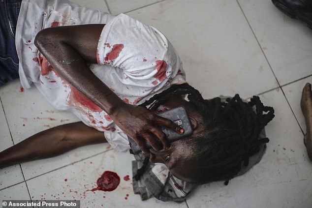 An injured journalist talks on the phone after being shot by armed gangs at the General Hospital in Port-au-Prince, Haiti