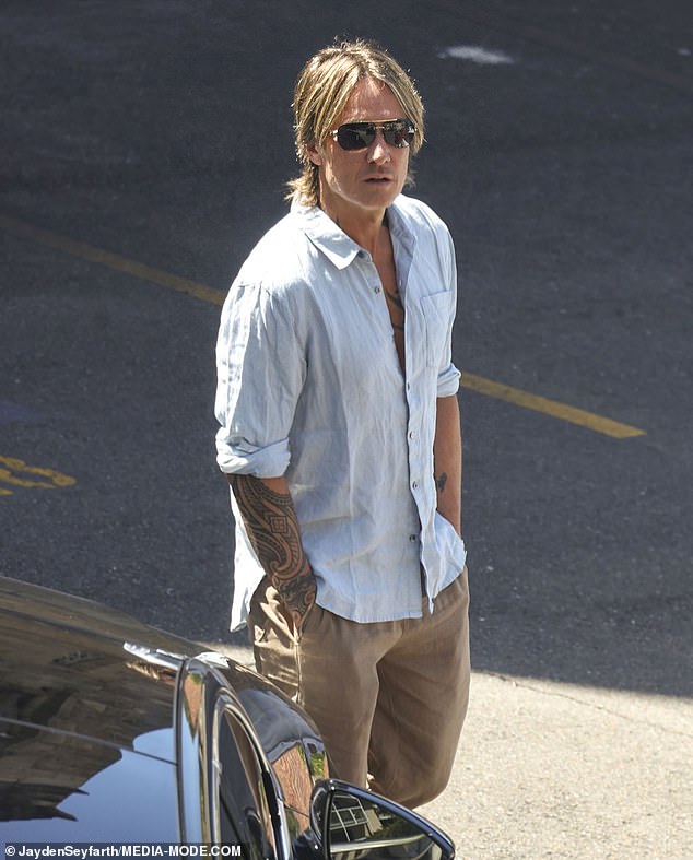 Keith showed off his tattooed arms as he basked in the sun while waiting next to their vehicle