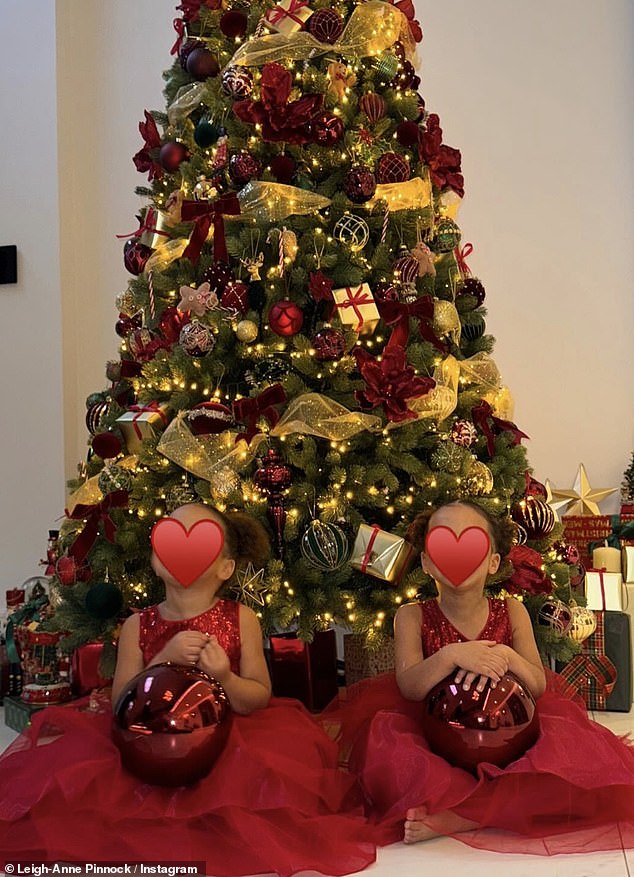 In other photos, the family posed happily beaming in front of the tree, while the singer covered the toddlers' faces with a red heart emoji