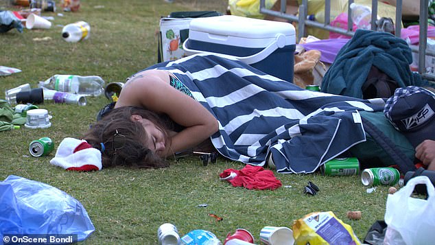 A bikini-clad partygoer was pictured lying under a towel amid the rubble, while council rangers estimated at least 10,000 tourists and backpackers were present