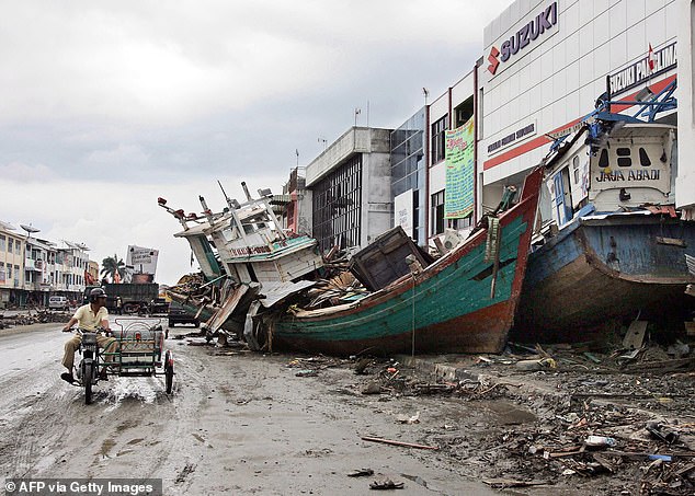 A motorist looks at boats pulled onto the streets during the 2004 tsunami in Banda Aceh