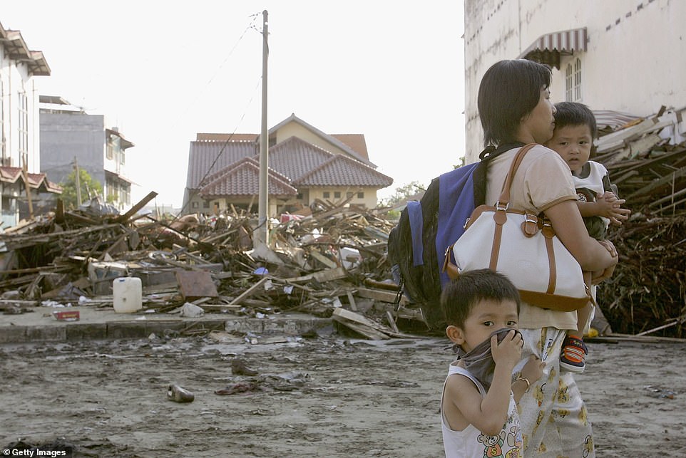 A mother and her children walked past rubble left on a street in Banda Aceh, Indonesia, days after the tsunami hit