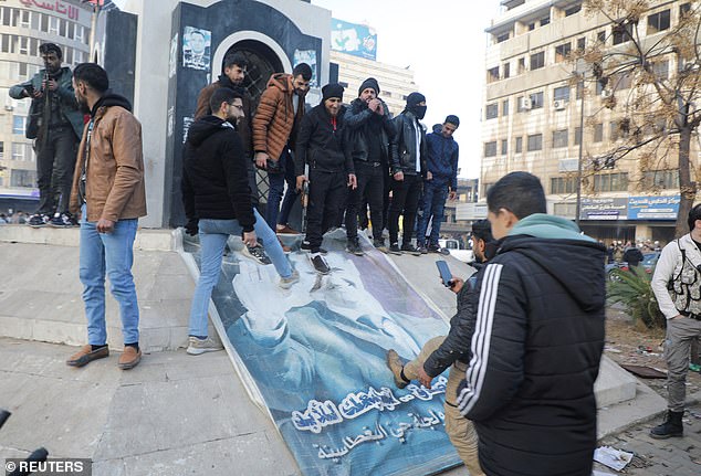 People kick a poster depicting Syrian President Bashar al-Assad after Syrian army leadership informed officers that al-Assad's 24-year rule had ended