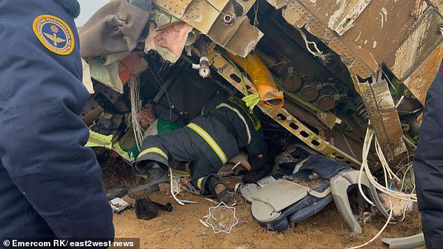 The photo shows rescuers crawling into the plane wreckage looking for survivors