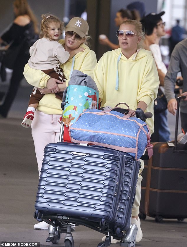 She completed her travel ensemble with a pair of white and fluorescent orange sneakers and a tan New York Yankees baseball cap