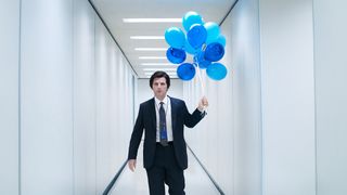 A still from a promo image for the second season of Severance, showing the character Mark with blue balloons in a hallway