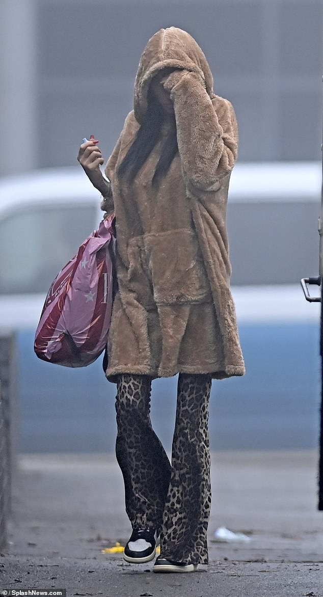 She donned Nike sneakers and carried a pink and red shopping bag as she stopped for a quick vape break before heading inside