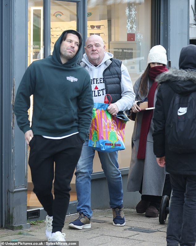 Mark cut a casual figure in a green graphic hoodie and black sweatpants, teamed with white trainers