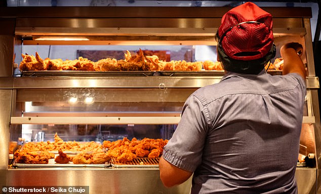 A fast food worker in a chicken shop (stock image). Researchers from University College London warned that highly processed foods, which often contain excessive amounts of salt and sugar, are often cheaper than fruit and vegetables