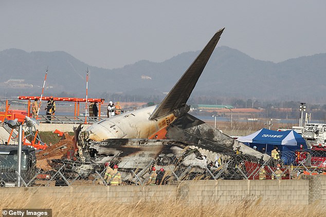 Firefighters and rescue teams work on the wreckage of a passenger plane at Muan International Airport