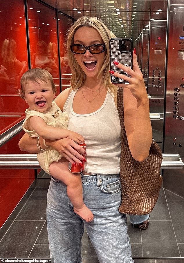 The Australian model was all smiles as she took an elevator selfie while cradling her giggling bundle of joy in one arm