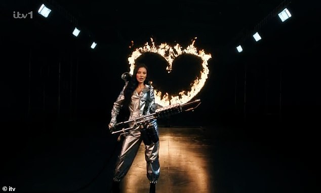 During the new teaser video, the Mayans appeared in a silver jumpsuit, complete with hood and silver mask, holding a flamethrower and a heart-shaped ring that lit up.