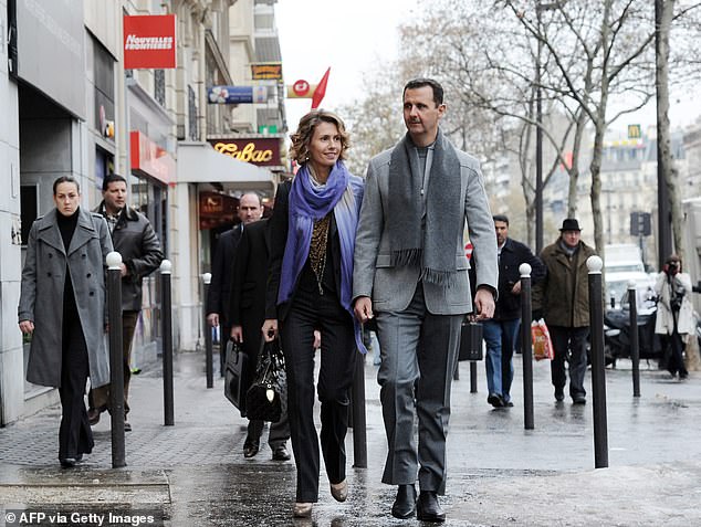 Bashar al-Assad and his wife Asma walk down a street in Paris on December 10, 2010