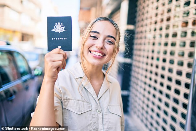 A young woman is pictured holding her Australian passport, now the most expensive in the world