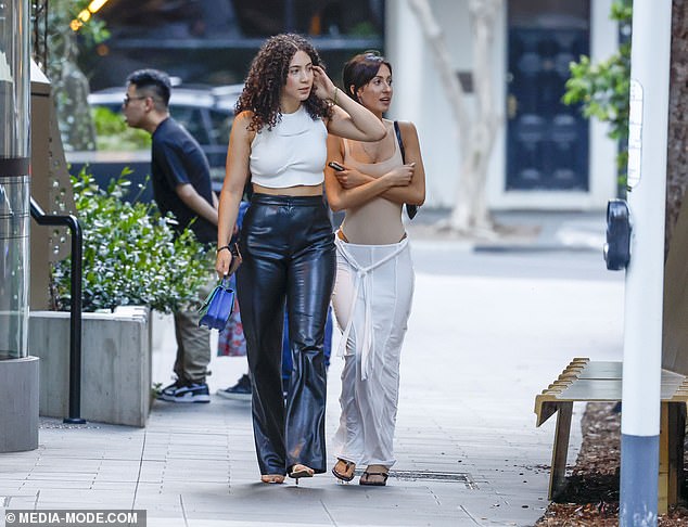 She strolled next to a friend who mirrored her edgy look in high-waisted leather pants and a white crop top