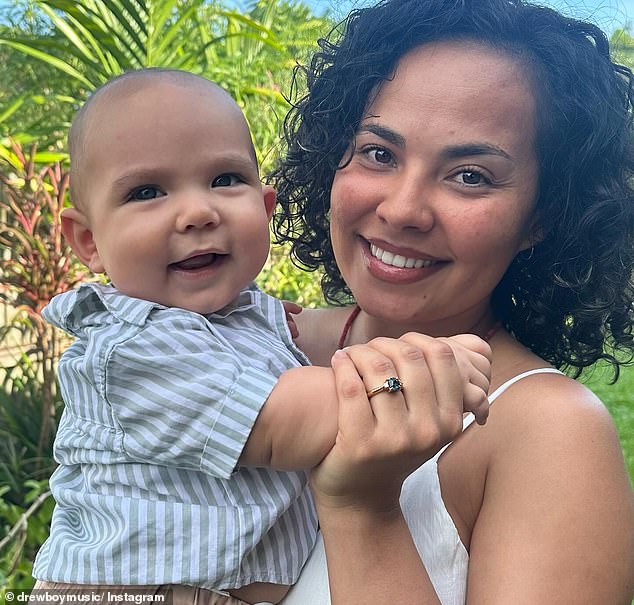 She beamed widely in another photo that showed off her statement engagement ring as she cuddled baby Rex, who the couple welcomed into the world in July.