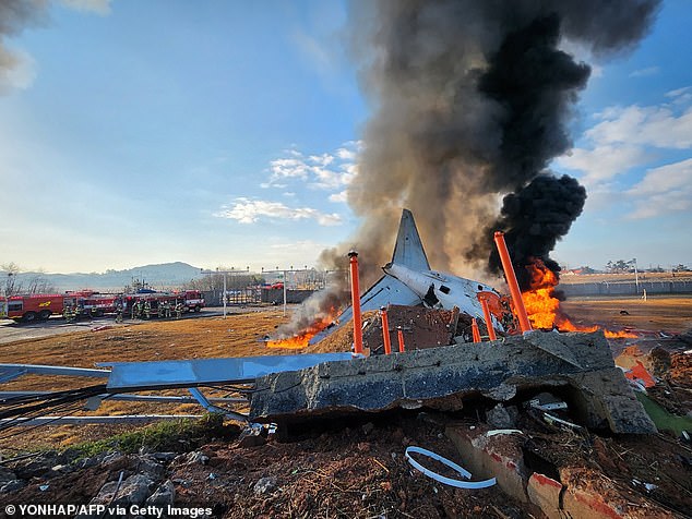 Fire and smoke rise from the tail section of a Jeju Air Boeing 737-800 series plane after the plane crashed and caught fire at Muan International Airport