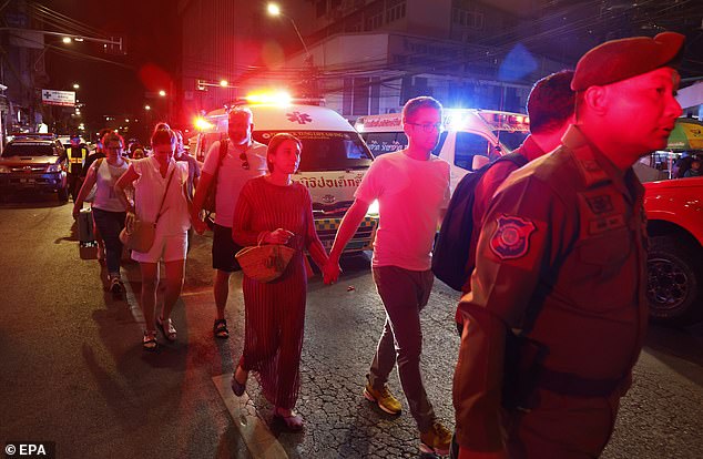 A police officer escorts tourists who have been evacuated from the hotel