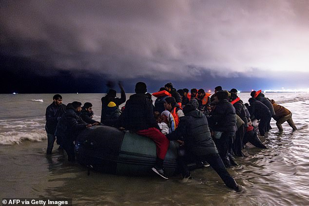 Migrants board a smuggler's inflatable rubber boat in an attempt to cross the English Channel, on Bleriot beach in Sangatte, near Calais, northern France on October 30, 2024