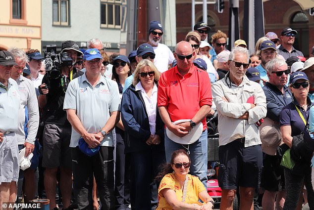 Two wreaths were placed at Constitution Dock, where Mr Smith and Mr Quaden would have set foot after finishing the race (people pictured gathering to honor Mr Smith and Mr Quaden)