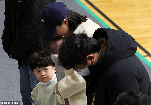 A child watches as mourners visit a memorial altar for the victims of the Jeju Air crash