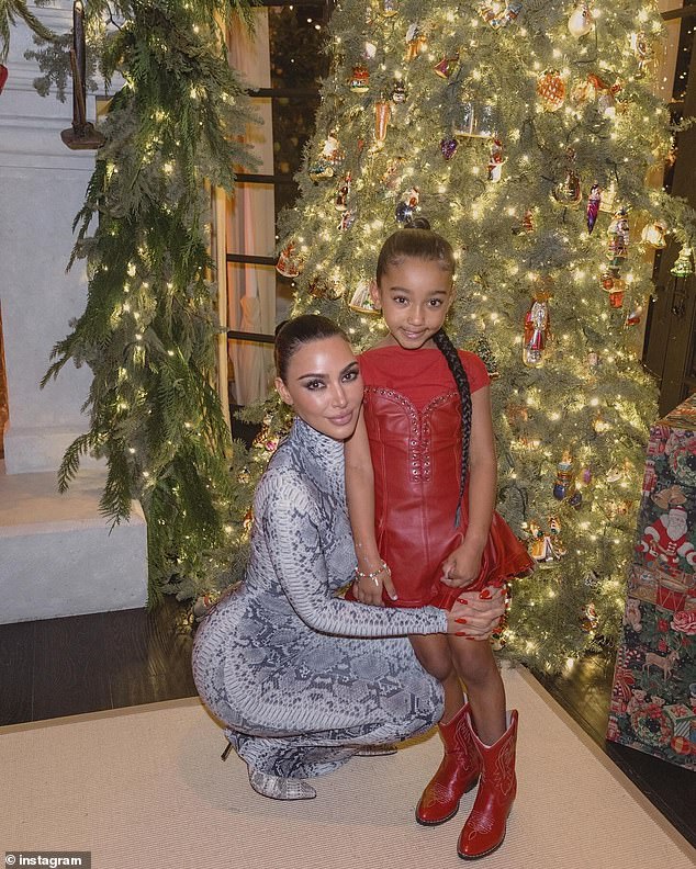 She posed dashingly by the Christmas tree and hunkered down low to cuddle with her youngest daughter Chicago, six.